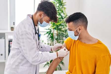 Foto de Dos hombres doctor y paciente pusieron una tirita en el brazo en la clínica - Imagen libre de derechos