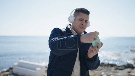 Foto de Joven hispano jugando videojuegos en la playa - Imagen libre de derechos