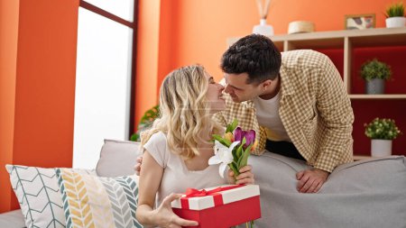 Téléchargez les photos : Homme et femme couple surprise avec cadeau et fleurs à la maison - en image libre de droit