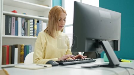 Foto de Joven estudiante rubia usando computadora estudiando en el aula universitaria - Imagen libre de derechos