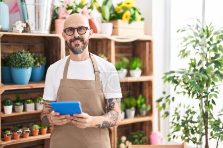 Photo for Young bald man florist smiling confident using touchpad at florist - Royalty Free Image