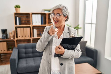 Photo for Middle age woman with grey hair at consultation office pointing fingers to camera with happy and funny face. good energy and vibes. - Royalty Free Image