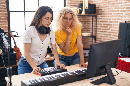 Téléchargez les photos : Deux femmes musiciens composant des chansons au clavier dans un studio de musique - en image libre de droit