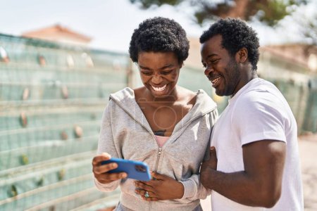 Téléchargez les photos : Africain américain homme et femme couple regarder la vidéo sur smartphone à la rue - en image libre de droit