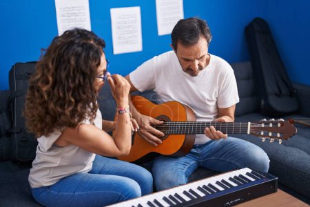 Photo for Man and woman musicians having classical guitar lesson at music studio - Royalty Free Image