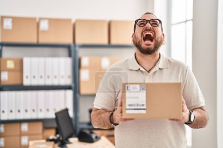 Photo for Plus size hispanic man with beard working at small business ecommerce angry and mad screaming frustrated and furious, shouting with anger looking up. - Royalty Free Image