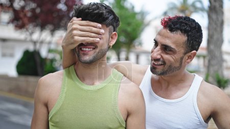 Foto de Dos hombres pareja sonriendo confiado cubriendo los ojos con la mano en la calle - Imagen libre de derechos