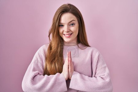 Photo for Young caucasian woman standing over pink background praying with hands together asking for forgiveness smiling confident. - Royalty Free Image