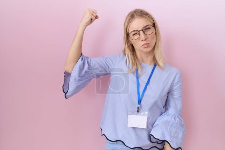 Photo for Young caucasian business woman wearing id card strong person showing arm muscle, confident and proud of power - Royalty Free Image