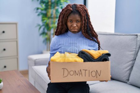 Photo for African woman holding donations box for charity depressed and worry for distress, crying angry and afraid. sad expression. - Royalty Free Image