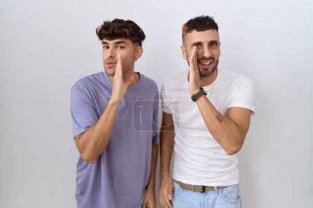 Foto de Homosexual gay pareja de pie sobre blanco fondo mano en boca diciendo secreto rumor, susurrando malicioso charla conversación - Imagen libre de derechos