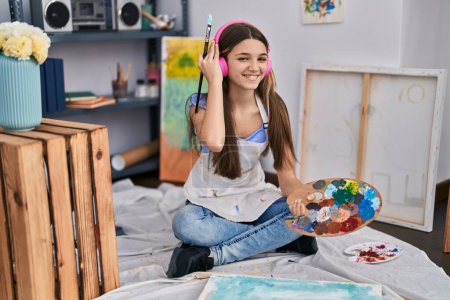 Photo for Adorable girl artist listening to music drawing at art studio - Royalty Free Image