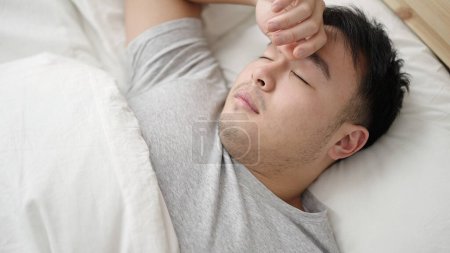 Foto de Joven hombre chino acostado en la cama durmiendo en el dormitorio - Imagen libre de derechos