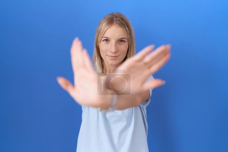Foto de Mujer caucásica joven usando casual azul camiseta rechazo expresión cruzando brazos y palmas haciendo signo negativo, cara enojada - Imagen libre de derechos