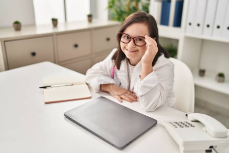 Photo for Down syndrome woman wearing doctor uniform smiling confident at clinic - Royalty Free Image