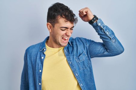 Téléchargez les photos : Jeune homme hispanique debout sur fond bleu dansant heureux et joyeux, souriant décontracté et confiant écoutant de la musique - en image libre de droit