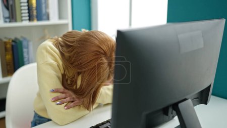Téléchargez les photos : Jeune étudiante blonde utilisant l'ordinateur et l'écriture sur ordinateur portable stressé à l'université salle de classe - en image libre de droit