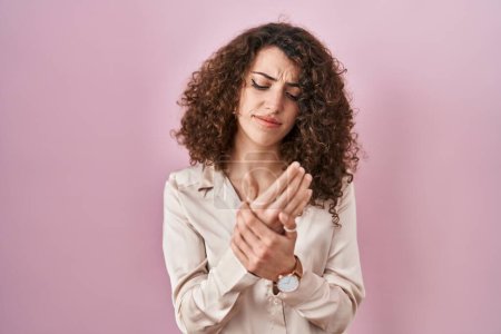 Photo for Hispanic woman with curly hair standing over pink background suffering pain on hands and fingers, arthritis inflammation - Royalty Free Image