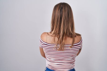 Foto de Mujer hispana joven de pie sobre fondo aislado de pie hacia atrás mirando hacia otro lado con los brazos cruzados - Imagen libre de derechos
