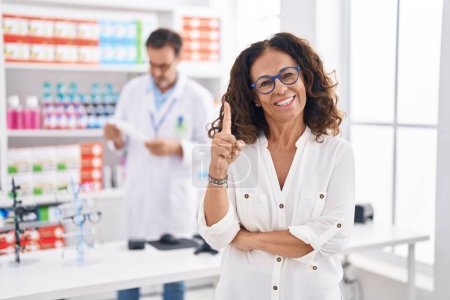 Téléchargez les photos : Femme hispanique du Moyen Age faisant ses courses à la pharmacie en souriant avec une idée ou une question pointant du doigt avec un visage heureux, numéro un - en image libre de droit