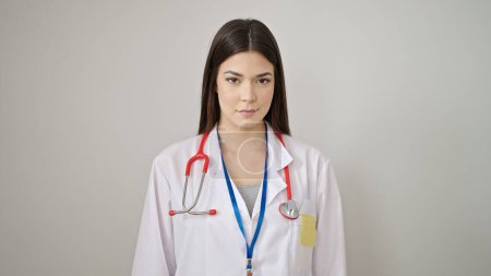 Foto de Joven hermosa doctora hispana de pie con expresión relajada sobre fondo blanco aislado - Imagen libre de derechos