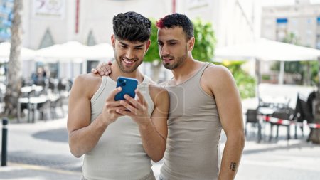 Téléchargez les photos : Two men couple smiling confident using smartphone at coffee shop terrace - en image libre de droit