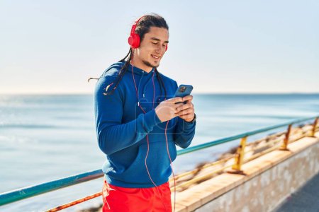 Foto de Young man listening to music at seaside - Imagen libre de derechos