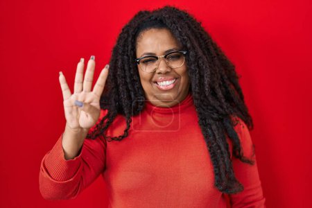 Photo for Plus size hispanic woman standing over red background showing and pointing up with fingers number four while smiling confident and happy. - Royalty Free Image