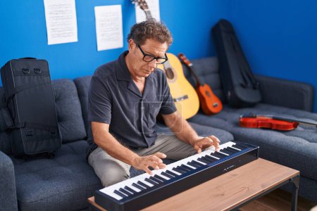 Foto de Hombre de mediana edad músico tocando el piano en el estudio de música - Imagen libre de derechos