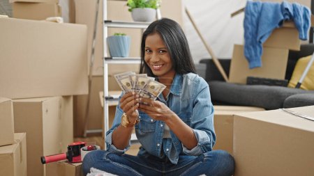 Photo for African american woman smiling confident counting dollars at new home - Royalty Free Image