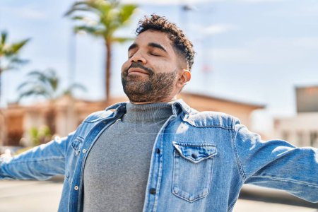 Téléchargez les photos : Young hispanic man smiling confident breathing at street - en image libre de droit