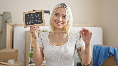 Photo for Young beautiful hispanic woman smiling confident holding new house keys and blackboard at new home - Royalty Free Image