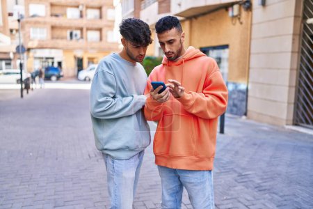 Foto de Two man couple using smartphone at street - Imagen libre de derechos