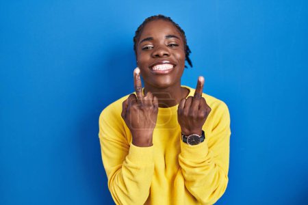 Foto de Beautiful black woman standing over blue background showing middle finger doing fuck you bad expression, provocation and rude attitude. screaming excited - Imagen libre de derechos