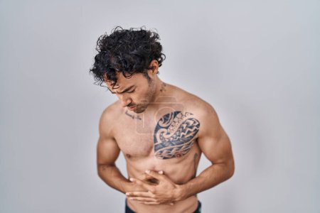 Téléchargez les photos : Homme hispanique debout torse nu avec la main sur le ventre parce que les nausées, la maladie douloureuse se sentent mal. concept de douleur. - en image libre de droit