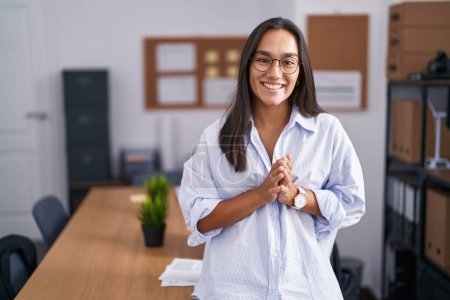 Téléchargez les photos : Jeune femme hispanique au bureau mains ensemble et doigts croisés souriant détendu et joyeux. succès et optimisme - en image libre de droit
