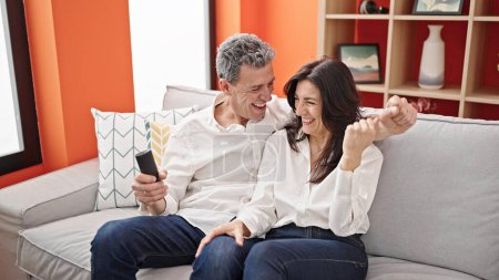 Téléchargez les photos : Senior homme et femme couple souriant confiant regarder la télévision à la maison - en image libre de droit