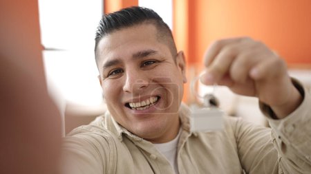 Foto de Joven hispano que tiene videollamada con llaves en su nuevo hogar - Imagen libre de derechos