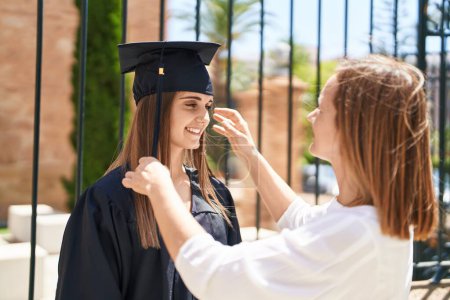 Photo for Two women mother and graduated daughter combing hair at campus university - Royalty Free Image