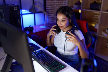 Photo for Young arab woman streamer sitting table with serious expression at gaming room - Royalty Free Image