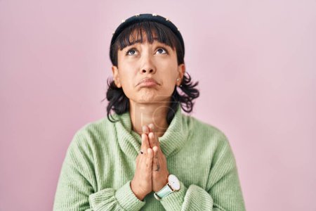 Photo for Young beautiful woman standing over pink background begging and praying with hands together with hope expression on face very emotional and worried. begging. - Royalty Free Image