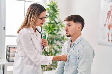 Photo for Young man and woman doctor and patient auscultating heart at clinic - Royalty Free Image