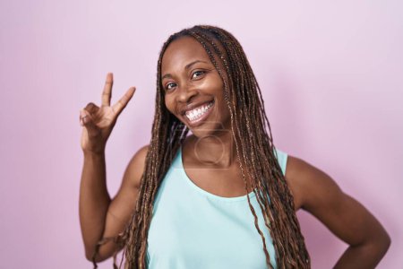 Photo for African american woman standing over pink background smiling looking to the camera showing fingers doing victory sign. number two. - Royalty Free Image