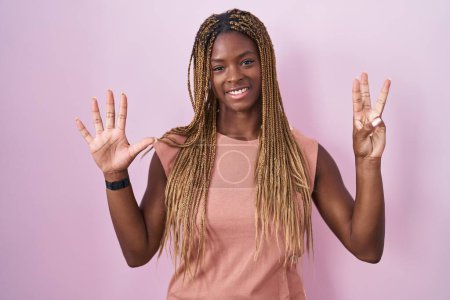 Photo for African american woman with braided hair standing over pink background showing and pointing up with fingers number eight while smiling confident and happy. - Royalty Free Image