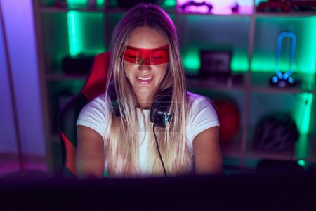 Photo for Young beautiful hispanic woman streamer playing video game using virtual reality glasses at gaming room - Royalty Free Image