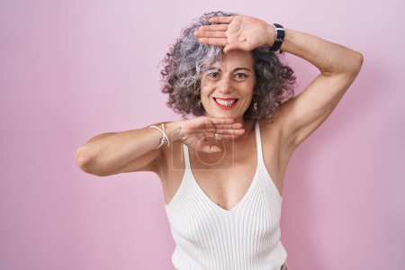 Photo for Middle age woman with grey hair standing over pink background smiling cheerful playing peek a boo with hands showing face. surprised and exited - Royalty Free Image