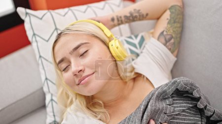 Young beautiful hispanic woman listening to music sleeping on sofa at home