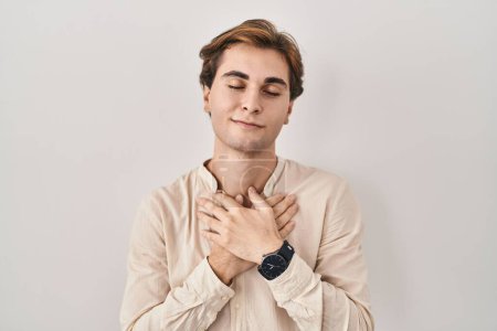 Photo for Young man standing over isolated background smiling with hands on chest with closed eyes and grateful gesture on face. health concept. - Royalty Free Image