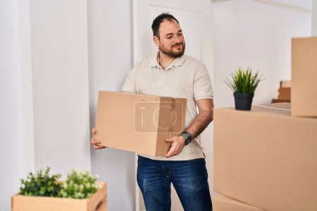 Photo for Young hispanic man smiling confident holding cardboard package at new home - Royalty Free Image