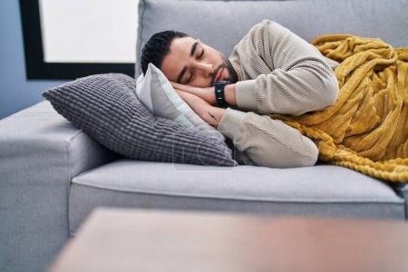 Téléchargez les photos : Jeune homme arabe couché sur le canapé dormant à la maison - en image libre de droit